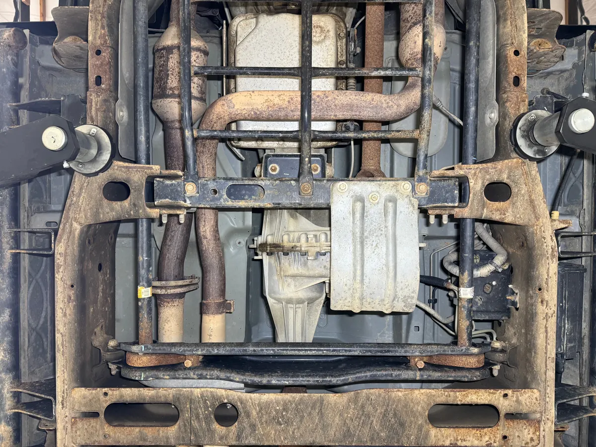 Hummer H2 frame rails and transmission crossmember before cleaning, covered in rust and road grime