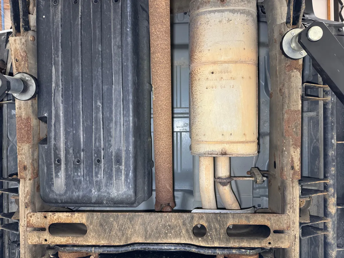 Hummer H2 frame rails alongside the fuel tank and muffler before cleaning